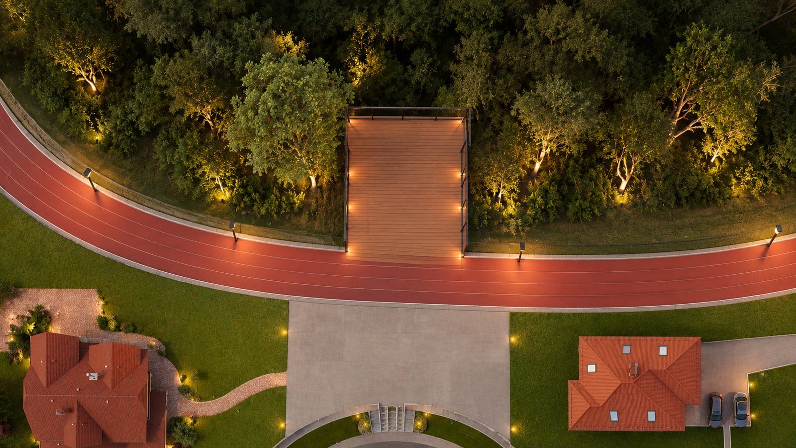 Vista aérea noturna da pista de caminhada iluminada e do deck de acesso ao bosque